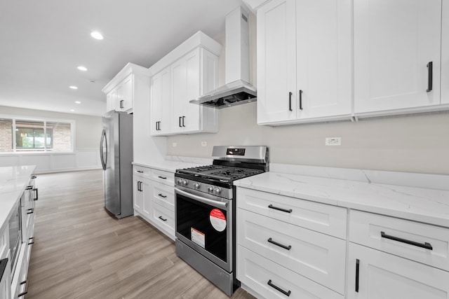 kitchen with wall chimney range hood, light wood-type flooring, light stone countertops, stainless steel appliances, and white cabinets