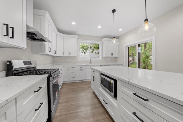 kitchen with appliances with stainless steel finishes, white cabinetry, and decorative light fixtures