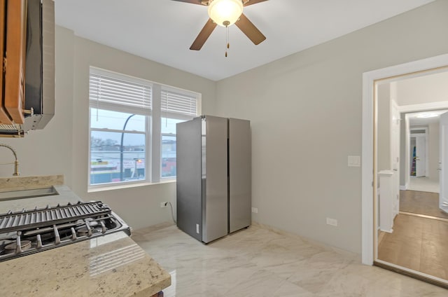 kitchen featuring light stone countertops, ceiling fan, stainless steel fridge, and sink