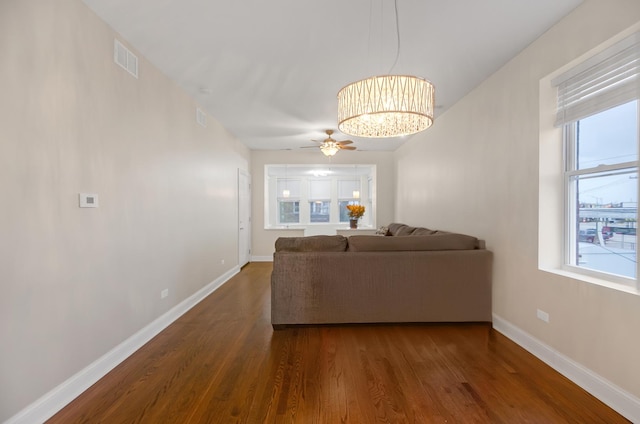 unfurnished living room featuring ceiling fan with notable chandelier and dark hardwood / wood-style floors