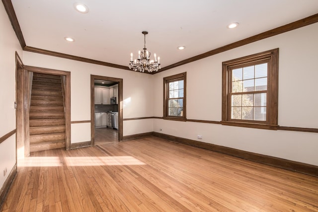 spare room with light wood-type flooring, crown molding, and an inviting chandelier