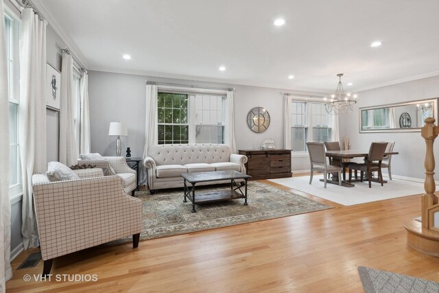 living room featuring ornamental molding, a notable chandelier, and light hardwood / wood-style floors