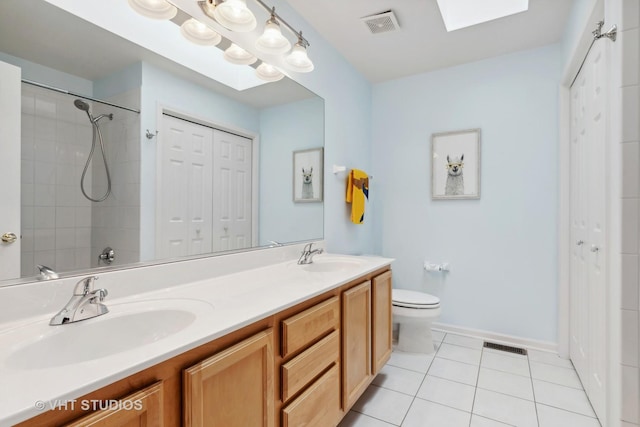 bathroom featuring vanity, tile patterned flooring, a skylight, and toilet