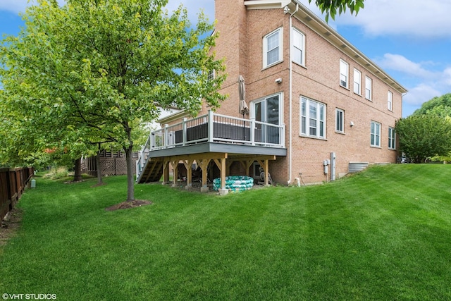 rear view of house with a wooden deck and a lawn