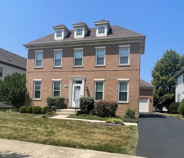 colonial inspired home featuring a garage and a front lawn