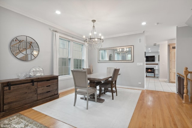 dining room with an inviting chandelier, crown molding, and light wood-type flooring