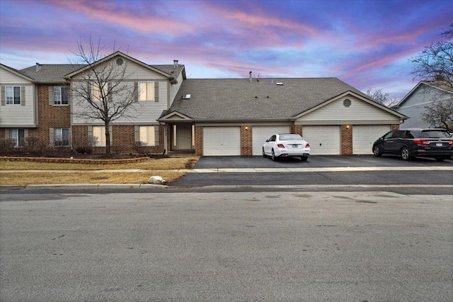 view of front of home featuring an attached garage, roof with shingles, aphalt driveway, and brick siding