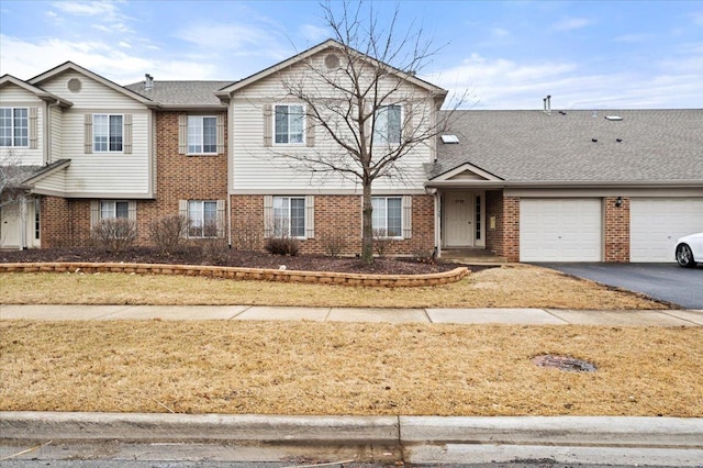 view of front of home featuring an attached garage, roof with shingles, aphalt driveway, and brick siding