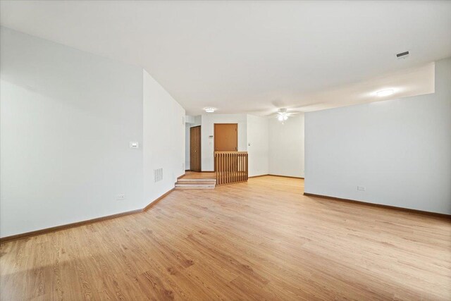 unfurnished room with visible vents, a ceiling fan, light wood-style flooring, and baseboards