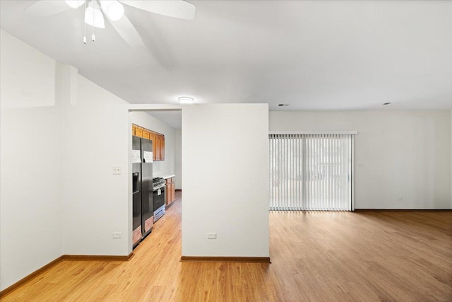 empty room featuring light wood-style floors, baseboards, and a ceiling fan