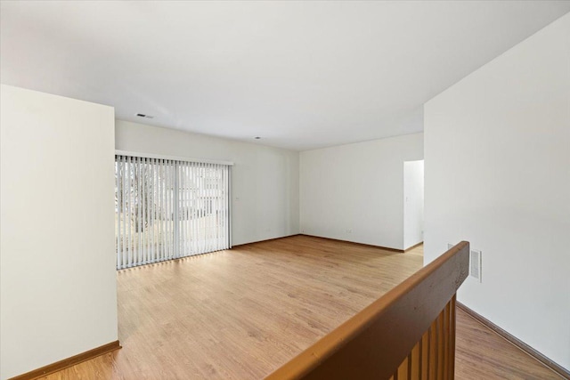 unfurnished room featuring visible vents, baseboards, and wood finished floors