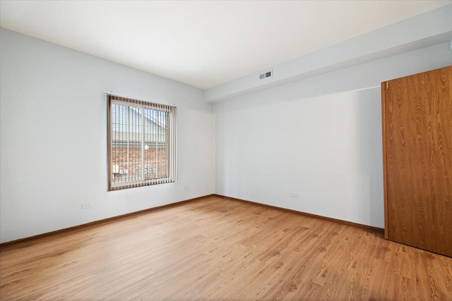 empty room with baseboards, visible vents, and light wood-style floors