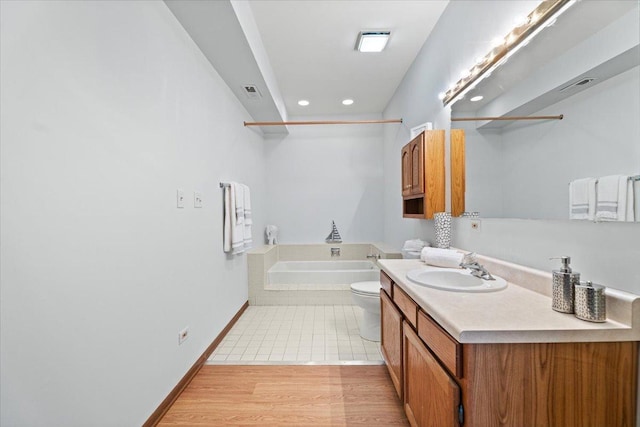 full bath with a garden tub, recessed lighting, wood finished floors, vanity, and baseboards