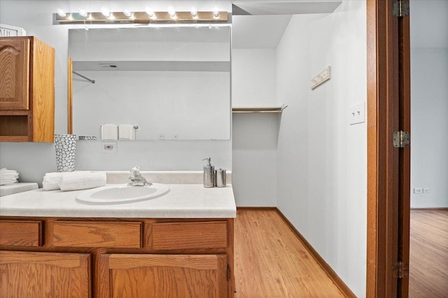 bathroom featuring wood finished floors, vanity, and baseboards