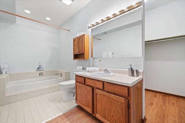 bathroom with a shower, toilet, wood finished floors, vanity, and a bath