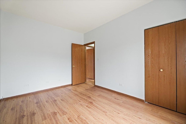 unfurnished bedroom featuring a closet, light wood-type flooring, and baseboards