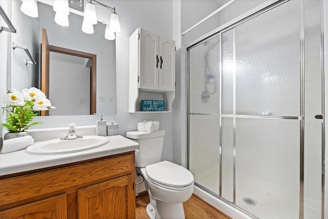 bathroom with a stall shower, vanity, toilet, and wood finished floors