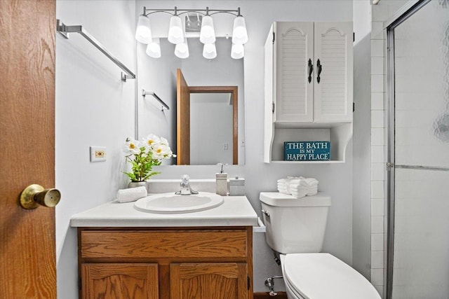 bathroom featuring toilet, a shower with shower door, and vanity