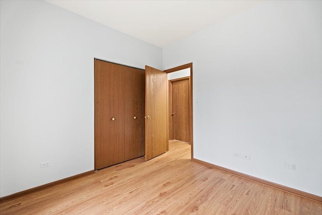 unfurnished bedroom featuring a closet, light wood-style flooring, and baseboards