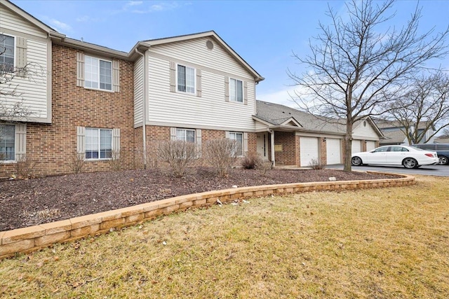 view of front of home with driveway, brick siding, a front lawn, and an attached garage