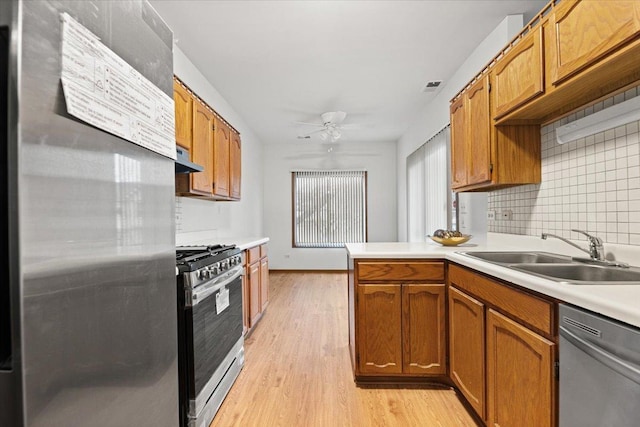 kitchen featuring light wood-style flooring, appliances with stainless steel finishes, light countertops, under cabinet range hood, and a sink