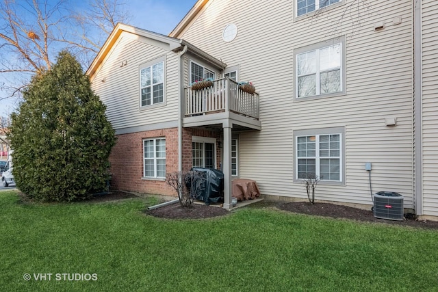 back of property with a lawn, a balcony, and central air condition unit