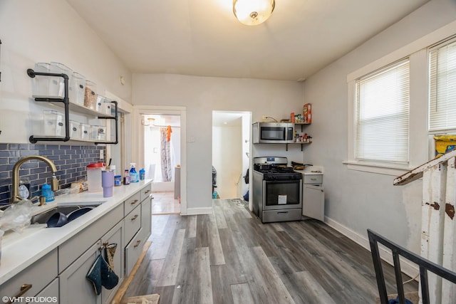 kitchen with appliances with stainless steel finishes, gray cabinetry, backsplash, dark hardwood / wood-style floors, and sink