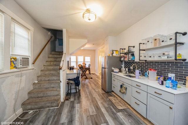 kitchen featuring tasteful backsplash, gray cabinets, hardwood / wood-style floors, stainless steel refrigerator, and sink