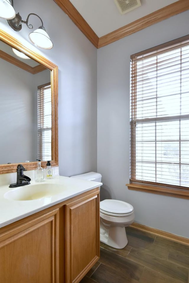 bathroom with vanity, a healthy amount of sunlight, crown molding, and toilet