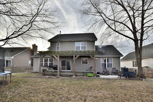 rear view of property with a trampoline, a pergola, a patio area, and a lawn