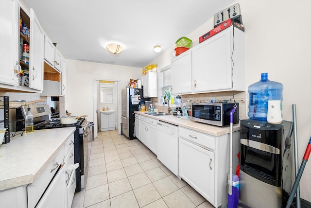 kitchen featuring white cabinets, appliances with stainless steel finishes, tasteful backsplash, sink, and light tile patterned floors