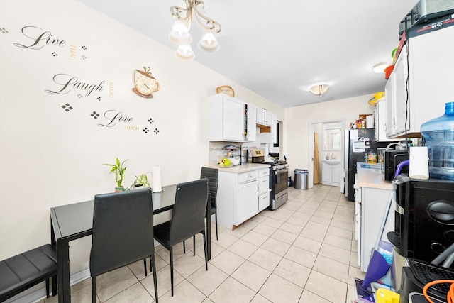 kitchen with white cabinets, appliances with stainless steel finishes, an inviting chandelier, tasteful backsplash, and light tile patterned floors