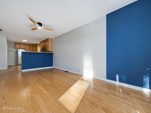 unfurnished living room featuring ceiling fan and light hardwood / wood-style flooring