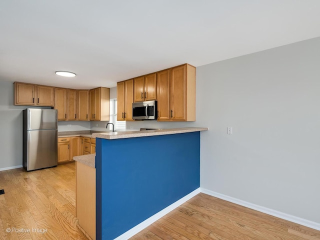 kitchen featuring kitchen peninsula, stainless steel appliances, and light wood-type flooring