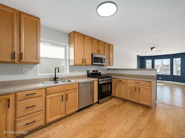 kitchen with ceiling fan, kitchen peninsula, sink, light hardwood / wood-style flooring, and appliances with stainless steel finishes