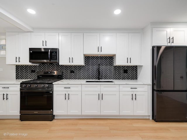 kitchen with light stone counters, sink, white cabinetry, and stainless steel appliances