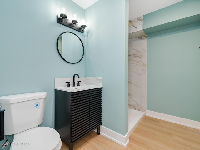 bathroom with toilet, vanity, tiled shower, and hardwood / wood-style floors