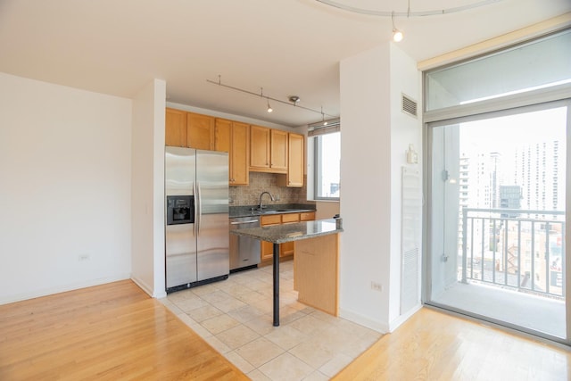 kitchen with light tile patterned floors, a kitchen bar, stainless steel appliances, decorative backsplash, and hanging light fixtures