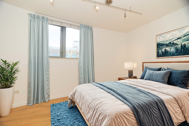 bedroom featuring rail lighting and light hardwood / wood-style flooring