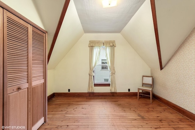 additional living space featuring light hardwood / wood-style flooring and lofted ceiling