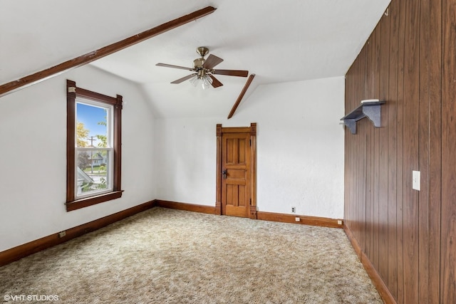 bonus room with vaulted ceiling, ceiling fan, carpet flooring, and wooden walls