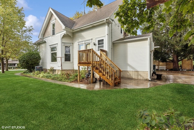 rear view of property with central AC unit and a lawn