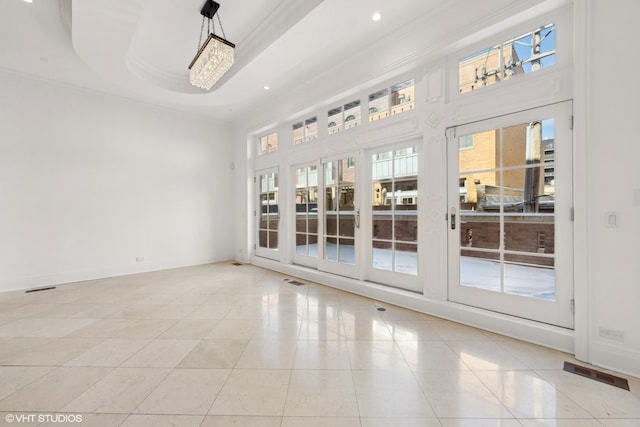 empty room with light tile patterned flooring, baseboards, a healthy amount of sunlight, a tray ceiling, and crown molding