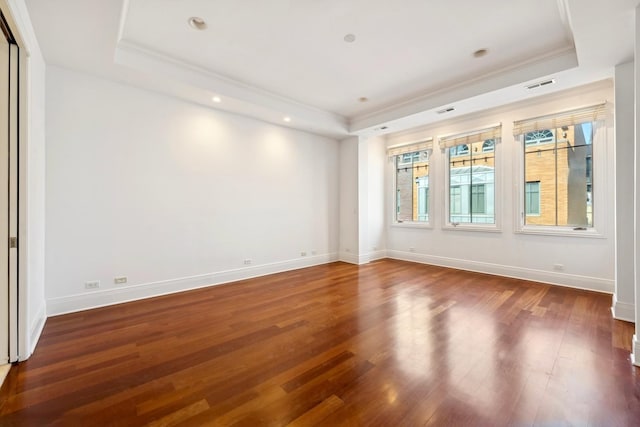 spare room featuring a tray ceiling, dark wood-style flooring, and baseboards