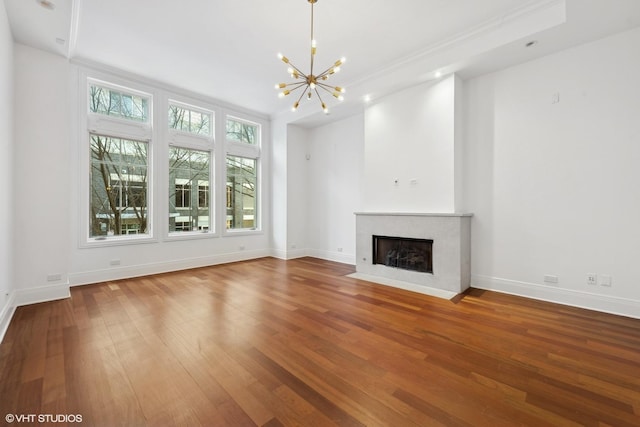 unfurnished living room with a fireplace with flush hearth, a healthy amount of sunlight, baseboards, and wood finished floors