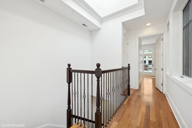 hall featuring crown molding, visible vents, an upstairs landing, light wood-type flooring, and baseboards