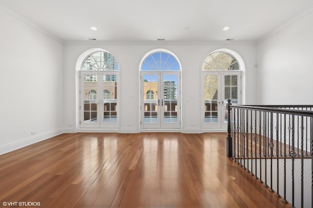 empty room with baseboards, recessed lighting, wood finished floors, and crown molding