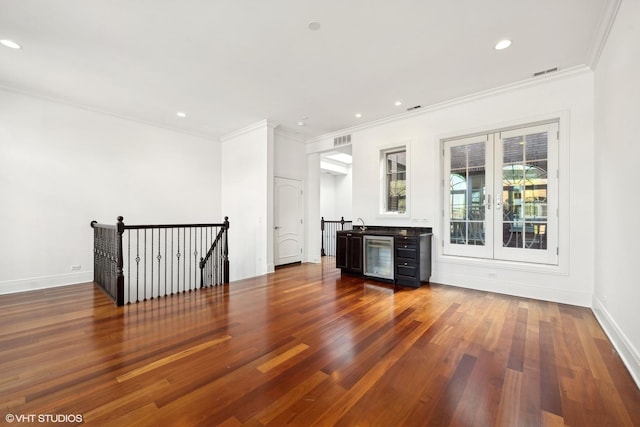 spare room featuring wine cooler, dark wood finished floors, visible vents, and baseboards