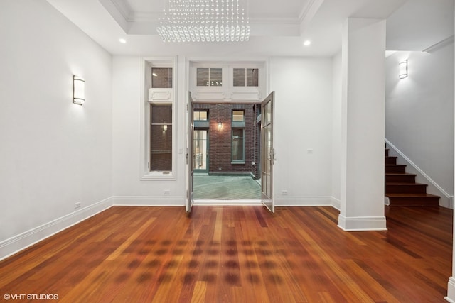 spare room with crown molding, a raised ceiling, and wood finished floors