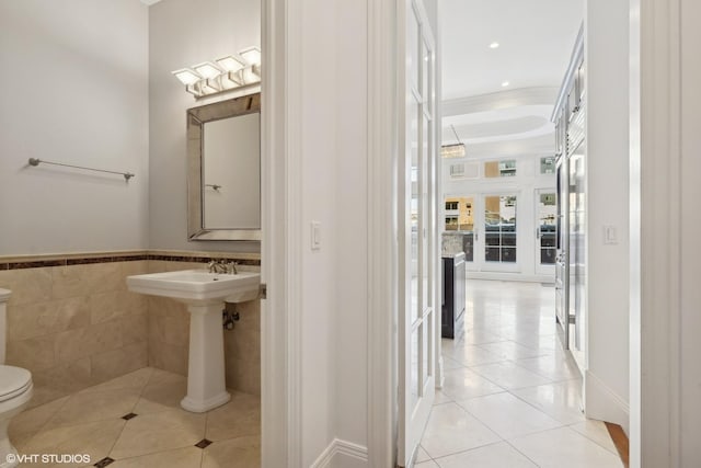 bathroom featuring a wainscoted wall, crown molding, tile walls, toilet, and tile patterned flooring